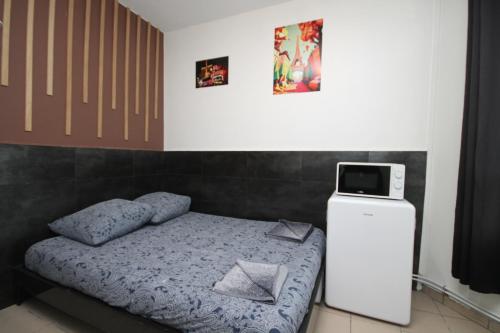 um pequeno quarto com uma cama e um pequeno frigorífico em 09 - Chambre proche Paris et Transports avec TV WIFI em Saint-Denis