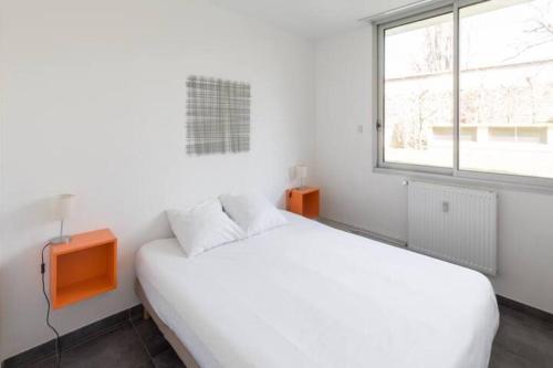 een witte slaapkamer met een bed en een raam bij Sereniva - Appartement Familial 2 chambres in Reims