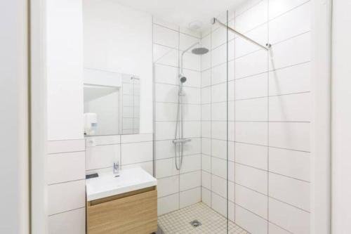 een witte badkamer met een wastafel en een spiegel bij Sereniva - Appartement Familial 2 chambres in Reims