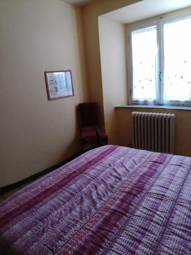 a bedroom with a bed and a window and a chair at Gli Aristogatti in Campo Tizzoro