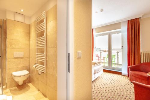 łazienka z toaletą oraz pokój z oknem w obiekcie Hotel Friese w mieście Norderney