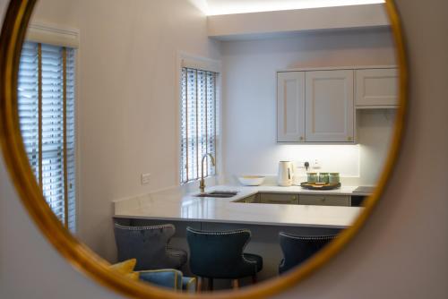 uma cozinha com um balcão e cadeiras num espelho em Hazelwick Apartment em Crawley