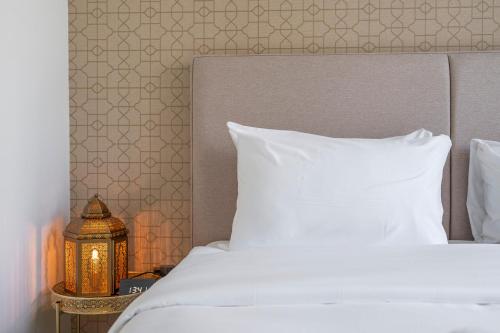 a bed with a white pillow and a nightstand with a moroccan at Elegant New 2BR l Spacious with Burj & Fountain Views l near Dubai Mall l Pool l Gym in Dubai