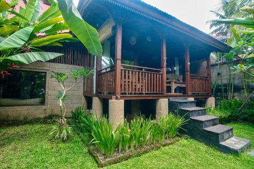 a house with a porch and stairs in a yard at The Banana’s Kumbe Villa in Tampaksiring