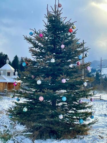 a christmas tree with ornaments on it in the snow at Садиба Карпат in Verkhovyna