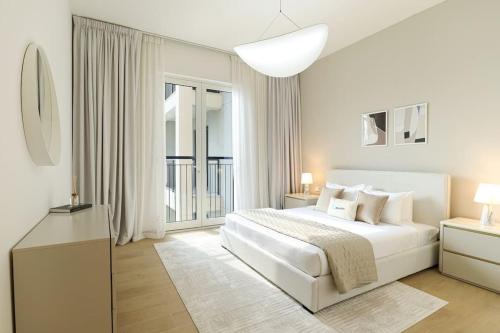 a white bedroom with a bed and a large window at HiGuests - Dream Vacation Apartment in La Rive 1 in Dubai