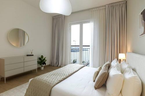 a bedroom with a white bed with a large window at HiGuests - Dream Vacation Apartment in La Rive 1 in Dubai