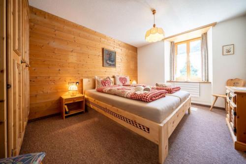 a bedroom with a bed and a wooden wall at Chasa Plazza Gronda in Lavin
