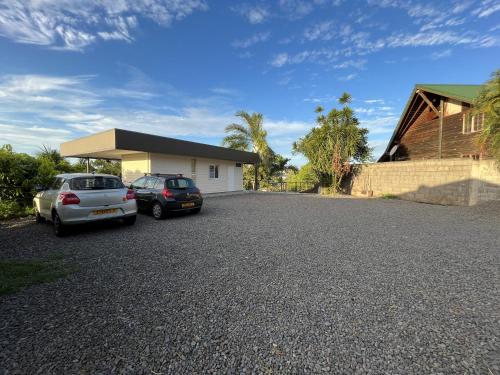 two cars parked in a parking lot in front of a house at Ononui Lodge Airport, Ocean-View, Private Bathroom and Balcony, Free WiFi and Parking, On-Site Car Rental in Faaa