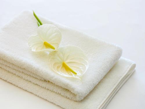 a white flower sitting on top of white towels at Mercure Wakayama Kushimoto Resort & Spa in Kushimoto
