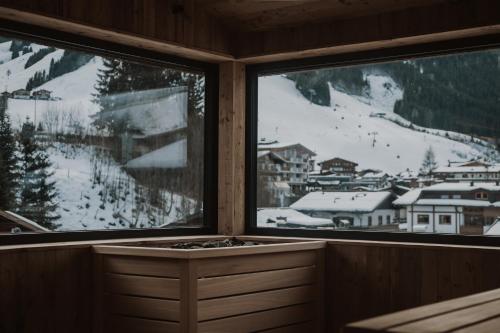 a room with a view of a snowy mountain through two windows at kerii - adults boutique hotel in Saalbach Hinterglemm