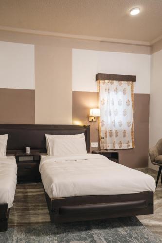a hotel room with two beds and a chair at Firebrick Boutique Residences - GARNET HOUSE in Gurgaon