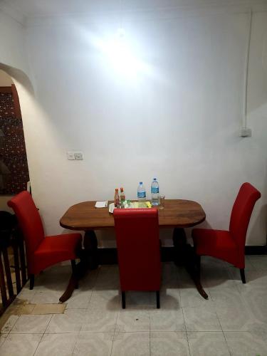 einen Tisch mit roten Stühlen und zwei Flaschen Wasser darauf in der Unterkunft Dwina Apartements in Mwanza