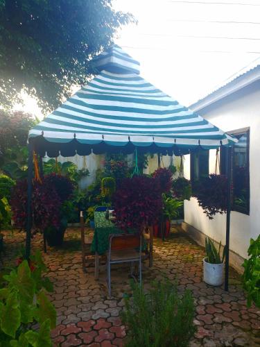 Dwina Apartements في موانزا: مظلة زرقاء وبيضاء مع طاولة وكراسي
