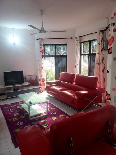 a living room with a red couch and a table at Dwina Apartements in Mwanza