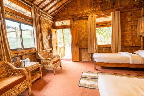 - une chambre avec 2 lits dans une maison en bois dans l'établissement HABITAS RHINO BY NATURE HUNT, à Kāziranga