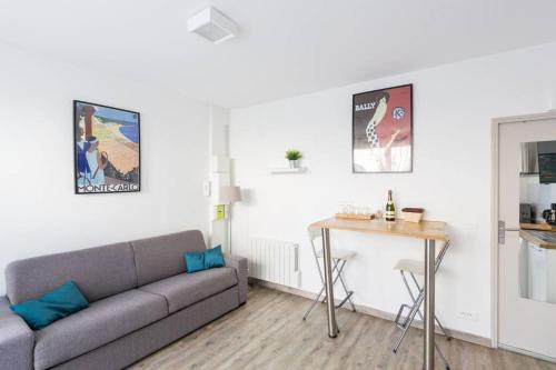 een woonkamer met een bank en een tafel bij Tranquilis - Studio hypercentre terrasse parking in Reims