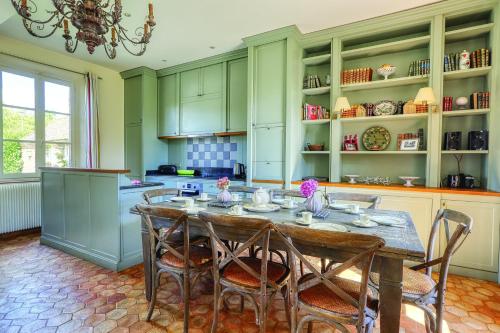 une cuisine avec une table et des chaises et une cuisine avec des armoires vertes dans l'établissement La Goupillère - Ancienne école totalement rénovée, à Heudicourt