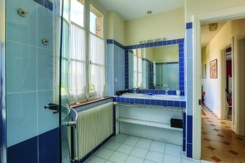 een blauwe badkamer met een wastafel en een spiegel bij La Goupillère - Ancienne école totalement rénovée 