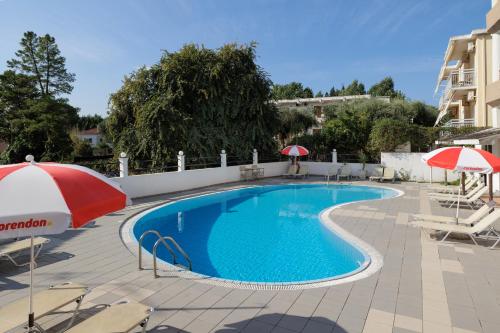 a swimming pool with chairs and umbrellas next to a building at Louvre Hotel in Gouvia