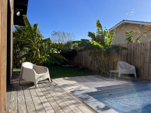 um pátio com 2 cadeiras, uma mesa e uma cerca em Villa avec piscine chauffée em Arès
