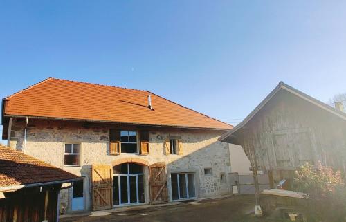 ein altes Steinhaus mit orangefarbenem Dach in der Unterkunft Au Coin Du Chemin in Chambéry
