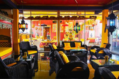 a restaurant with yellow and black chairs and tables at Tanah Merah Art Resort by AGATA in Ubud