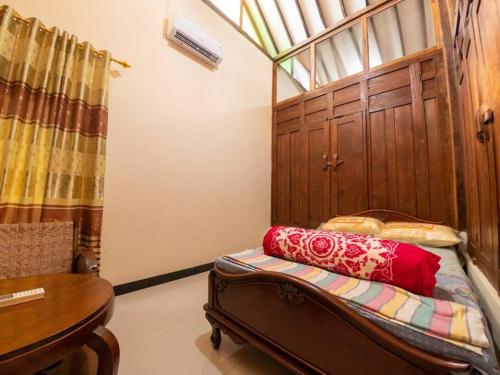 a bedroom with a bed and a table and a window at Kampung house Godean Sleman Yogyakarta in Godean