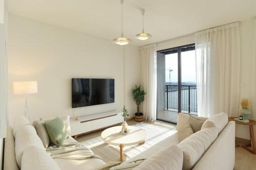 a living room with a white couch and a large window at HiGuests - Family Dream Escape with Private Beach Access in Dubai