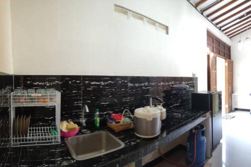 uma cozinha com um balcão preto e um lavatório em Kampung house Godean Sleman Yogyakarta em Godean