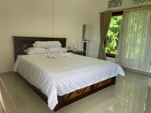 a bedroom with a large white bed with a window at Sri Sedana Guest House in Sidemen