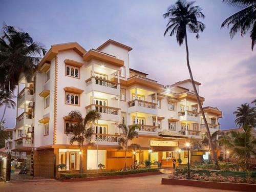 un edificio con palmeras delante en Goa Villagio Resort & Spa - A unit of IHM, en Betalbatim