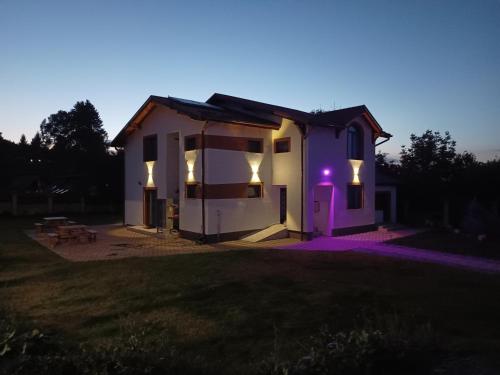 ein kleines weißes Haus mit lila Lichtern drauf in der Unterkunft MONADIN Villa Relax & Spa in Săcele