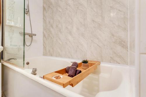 a bathroom with a bathtub with a wooden tray with towels at Spacious 1 Bed next to Baker St in London