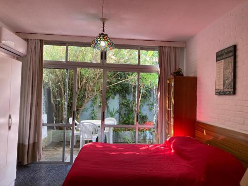 1 dormitorio con cama roja y ventana grande en Monoambiente Parada 5 Playa Brava - Punta del Este, en Punta del Este