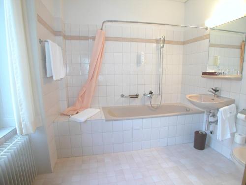 a bathroom with a bath tub and a sink at Hotel Post Glarnerhof in Glarus