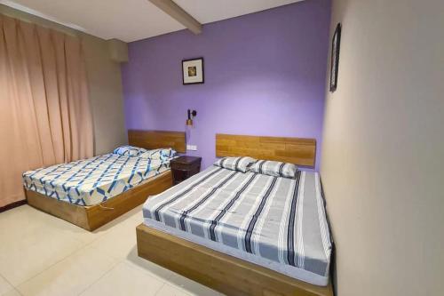 two beds in a room with purple walls at OYO 90883 Pavilion Inn Hotel in Lumut