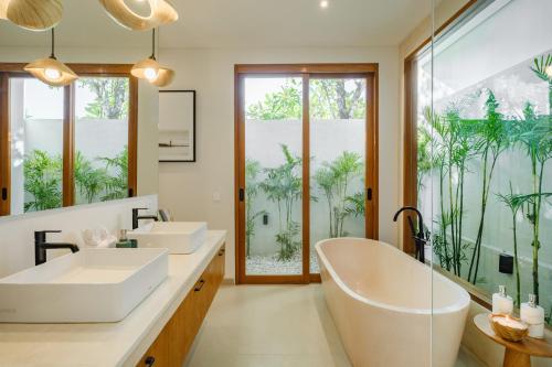 a bathroom with two sinks and two mirrors at Las Hermanas Villa by MAR Bali in Dalung