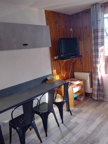 a living room with a table with chairs and a television at chamois tétras marmotte in Allos