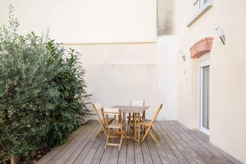 une table et des chaises en bois sur une terrasse dans l'établissement Eclipsa - Appartement de charme centre-ville, à Reims