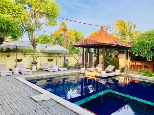 a swimming pool with chairs and a gazebo at Pondok Baruna Garden in Nusa Lembongan