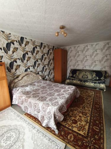 a small bedroom with a bed and a rug at Уютная квартира в центре города in Karagandy