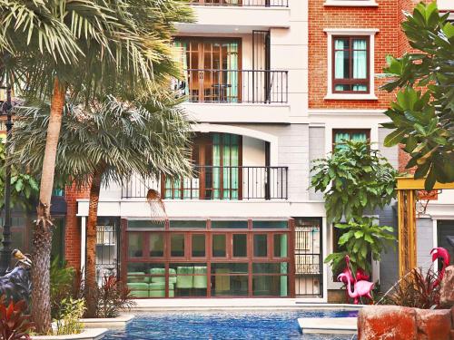 a building with palm trees and a swimming pool at Espana Vacation Residence Jomtien & Yahaha in Pattaya South