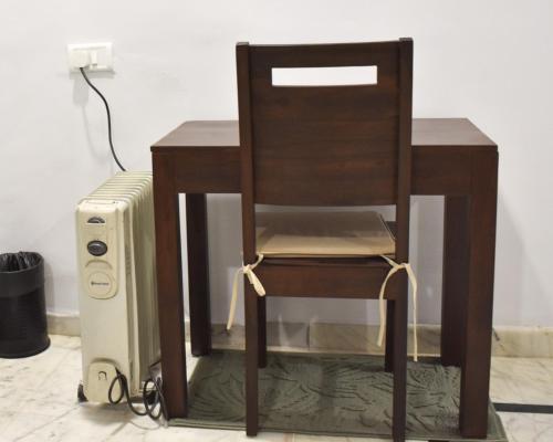 a wooden chair sitting next to a desk with a router at Firebrick Boutique Residences - GARNET HOUSE in Gurgaon