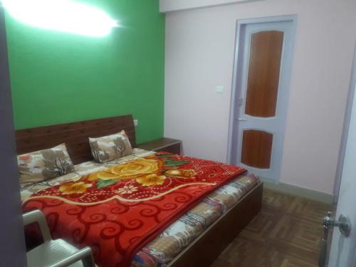 - une chambre avec un lit doté d'une couverture rouge et de fleurs jaunes dans l'établissement Hateshwari Guest House, à Shimla