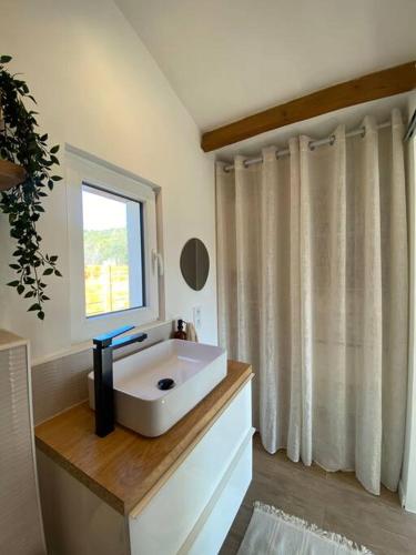 een badkamer met een witte wastafel en een raam bij Maisonnette cosy à la campagne in Céret