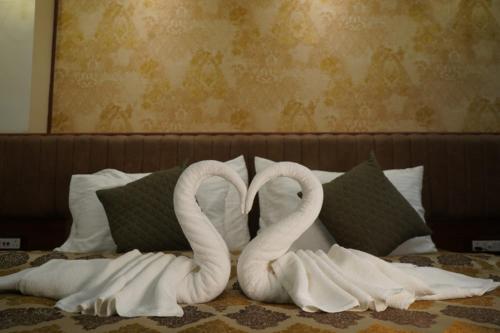 two towel swans are forming a heart on a bed at Swet Palash Resort in Purulia