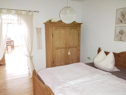 Schlafzimmer mit einem weißen Bett und einem Holzschrank in der Unterkunft Thüringer Pforte in Gorsleben
