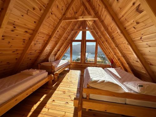 two beds in a wooden room with a window at Zaovinska idila in Bjeluša