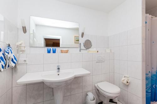 ein weißes Bad mit einem Waschbecken und einem WC in der Unterkunft Hotel Kiek ut in Pellworm